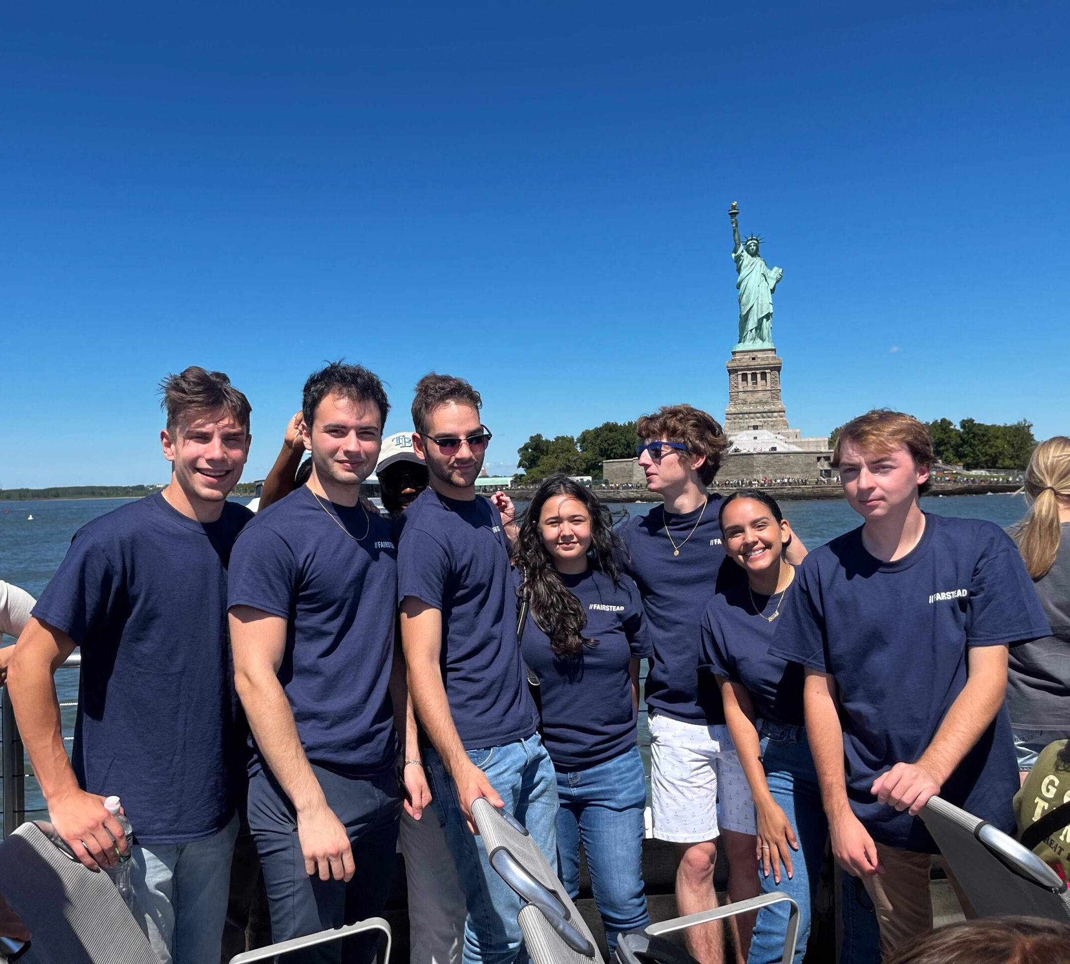Group of interns on a boat tour in front of statue of liberty